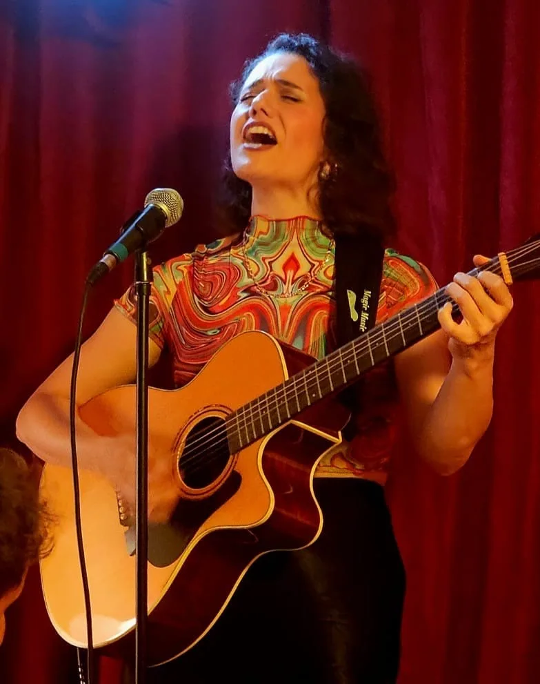 Melania Maggiore singing and playing guitar at her debut EP launch in The Cave, Crystal Palace